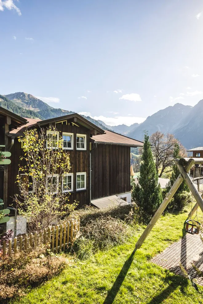 Kurzurlaub im Alphotel Alpenhäuser mit Blumenbalkonen und Spielplatz in sonniger Berglandschaft